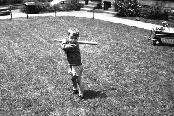 Young jack swinging a baseball bat in the park.